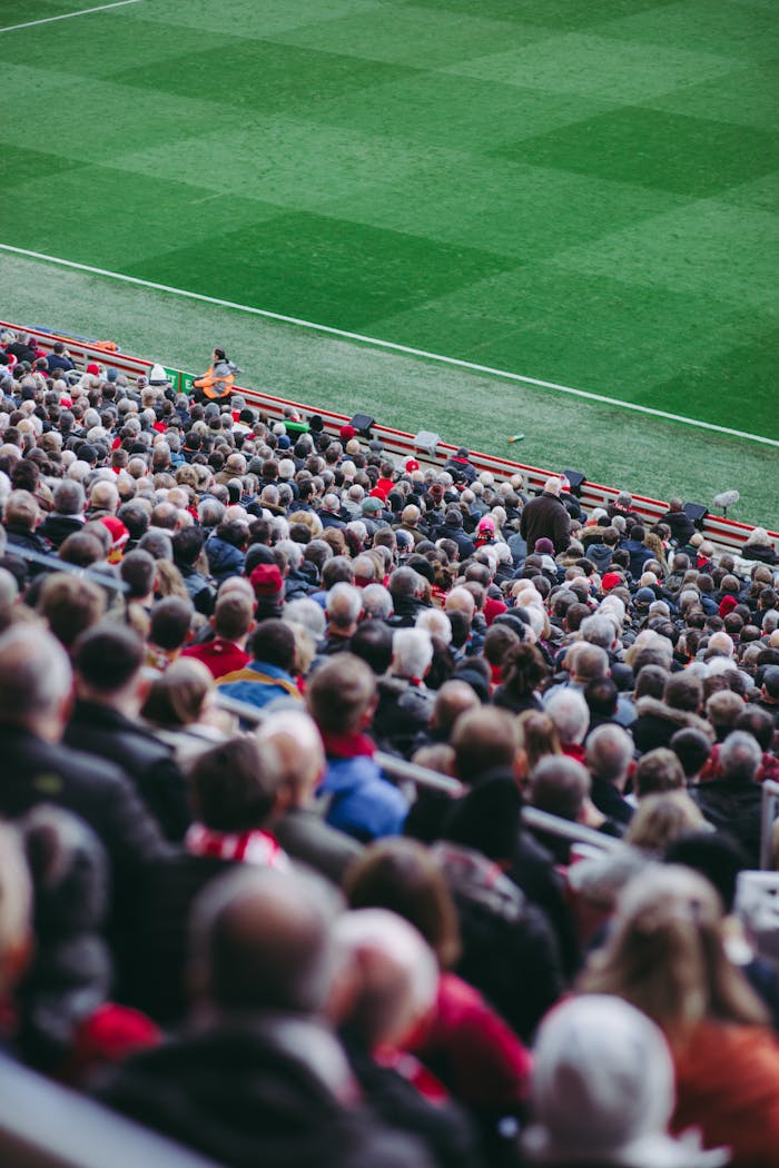 A lively crowd of soccer fans watching a game in an English stadium.